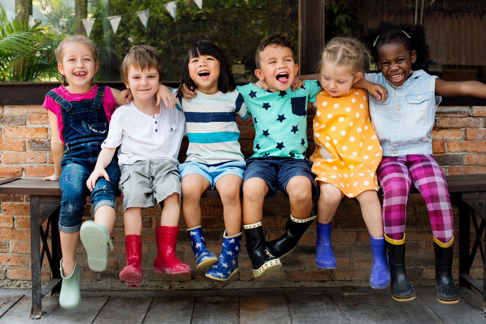 Diverse race, kindergarten kids friends arm around sitting smiling